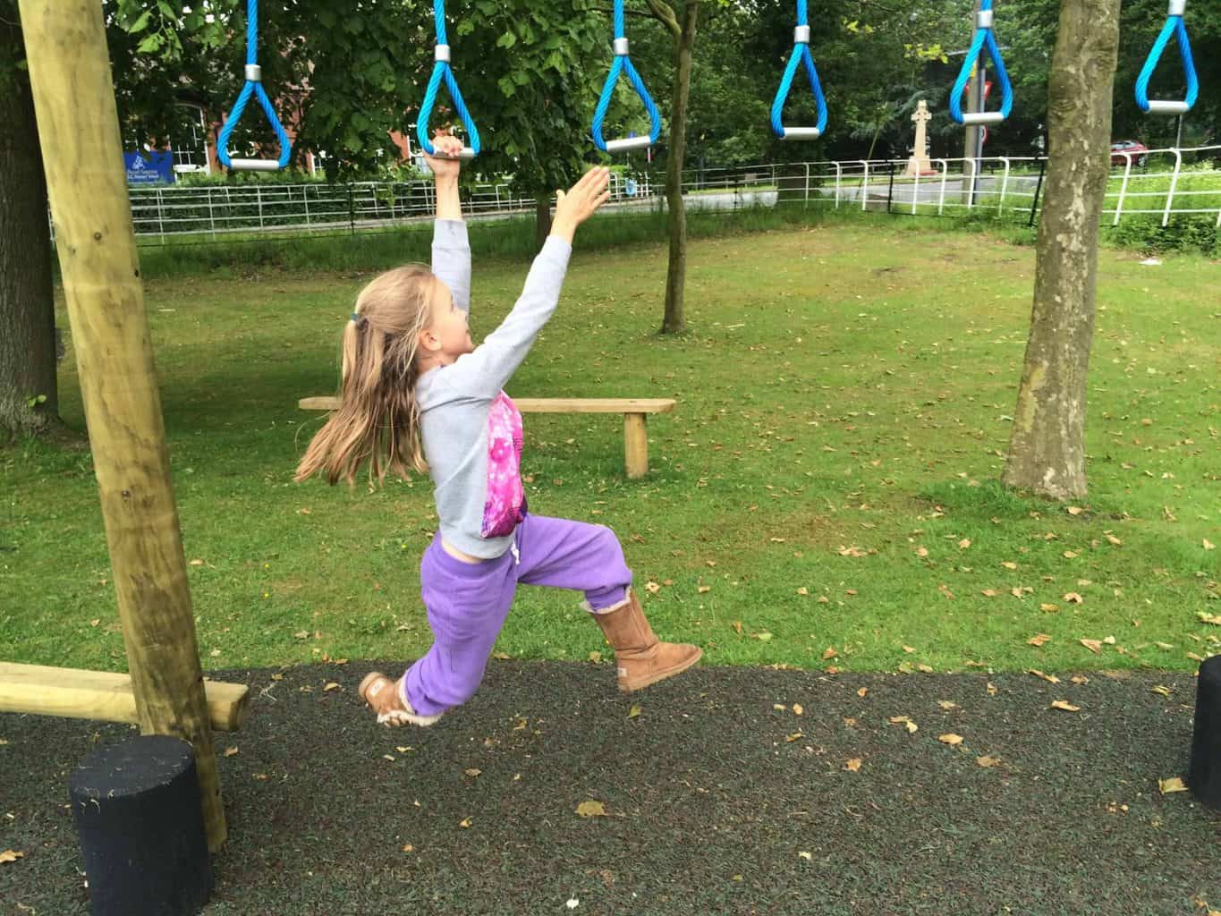 Little girl swinging on monkey bars