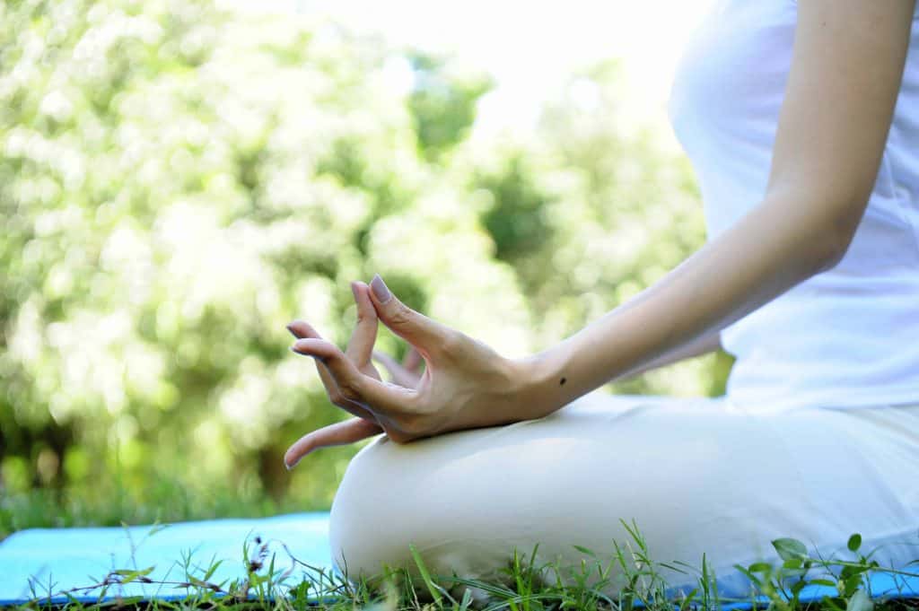 Woman wears white doing meditation in the park