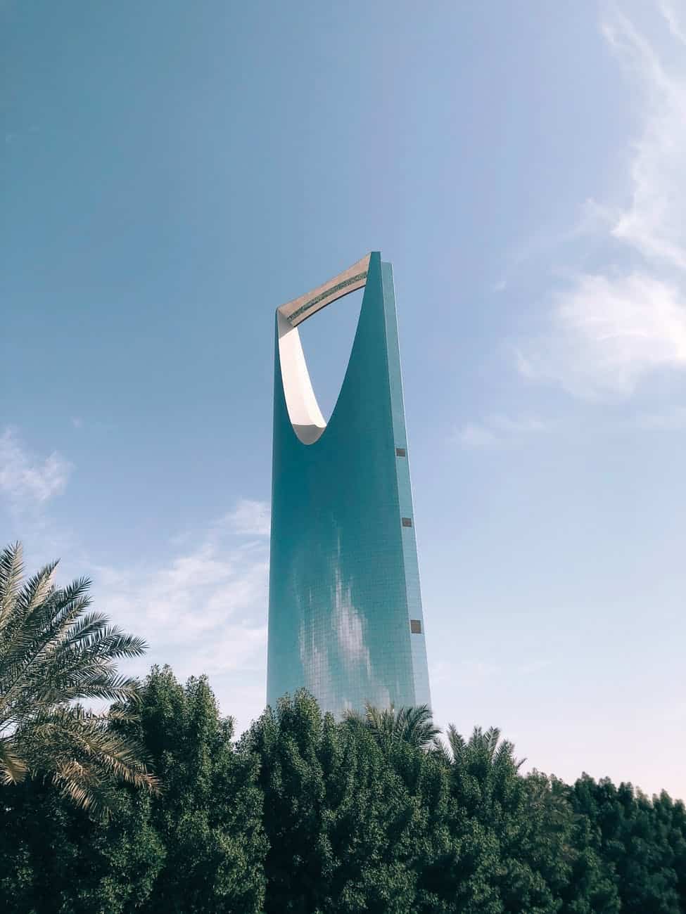 high rise building behind trees under blue sky in Riyadh Saudi Arabia