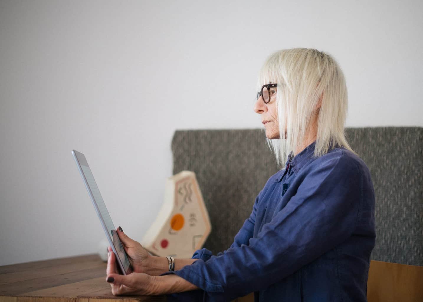 aged woman using tablet while sitting at home