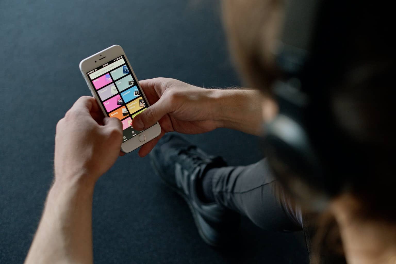 person with headphones holding a smartphone