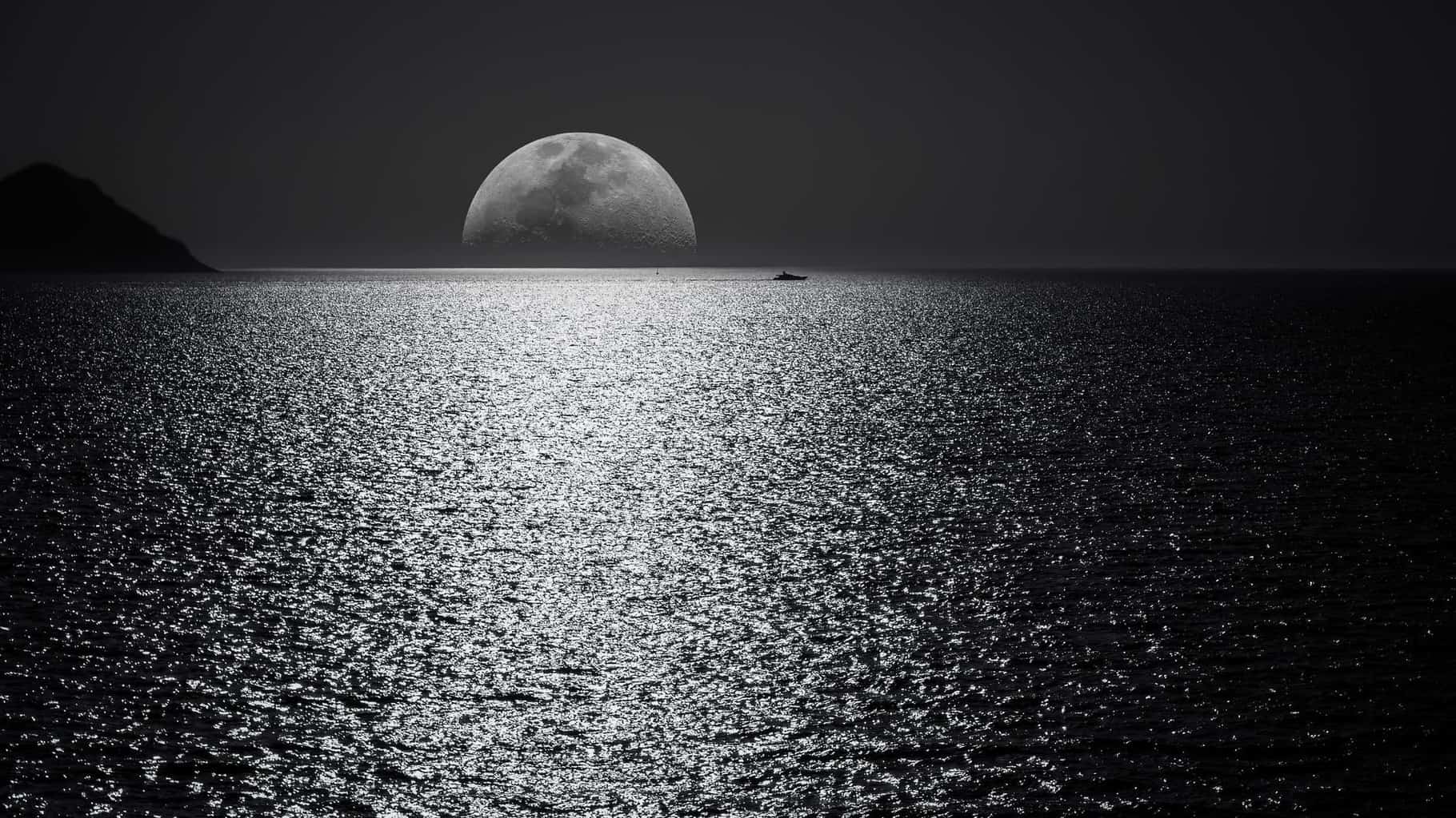 white and black moon with black skies and body of water photography during night time