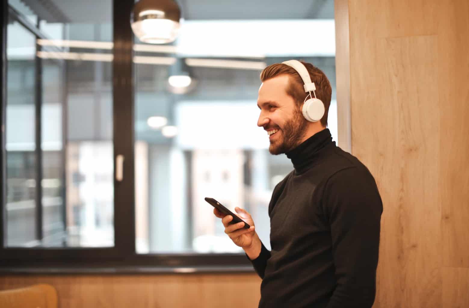 man wearing black long sleeve shirt while holding black smartphone