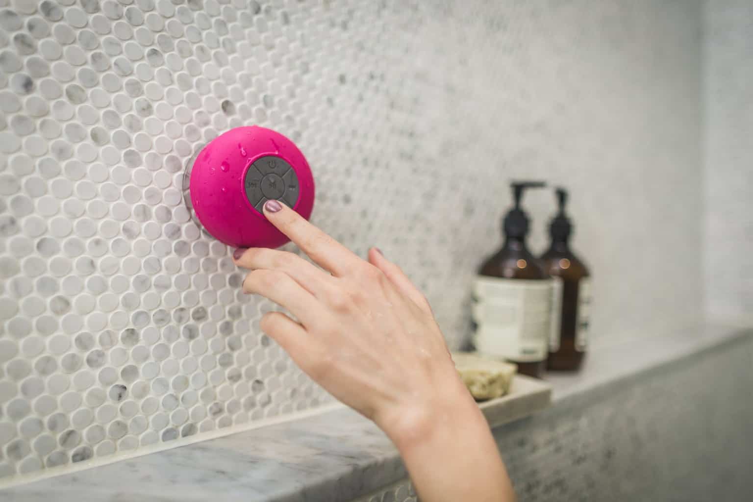 person touching a bluetooth speaker