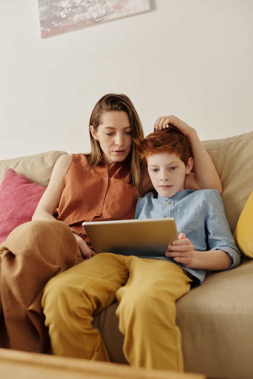 photo of woman and boy watching through tablet computer