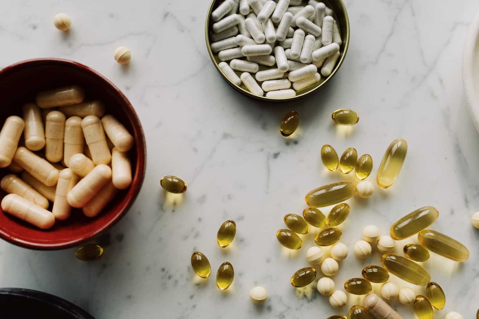 vitamins and drugs of different sizes on various tableware on marble board