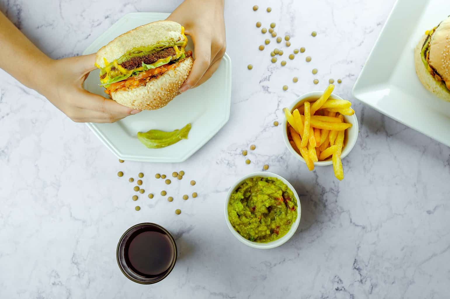 unrecognizable person eating hamburger in daytime