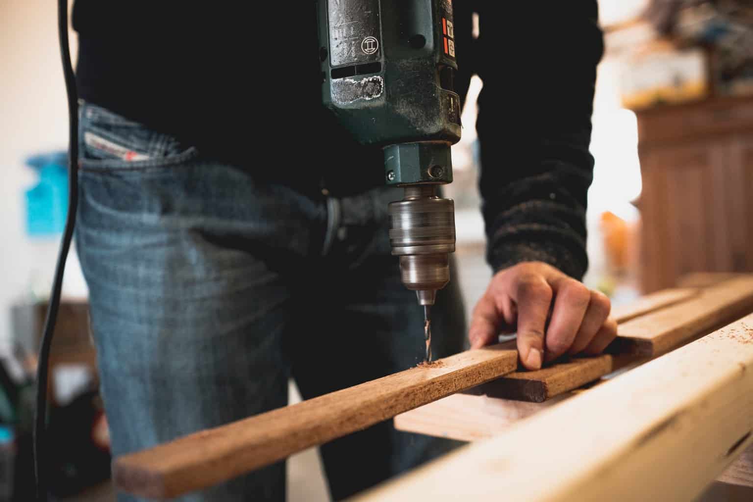 man holding wooden stick while drilling hole