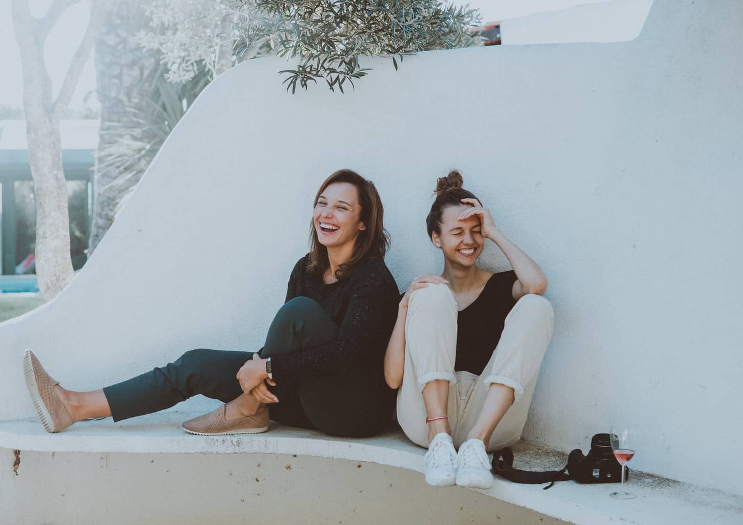 two women sitting on white bench