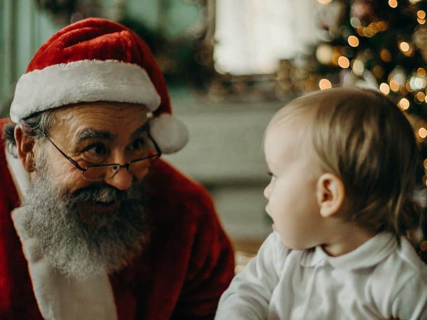 man in santa claus costume looking at a baby