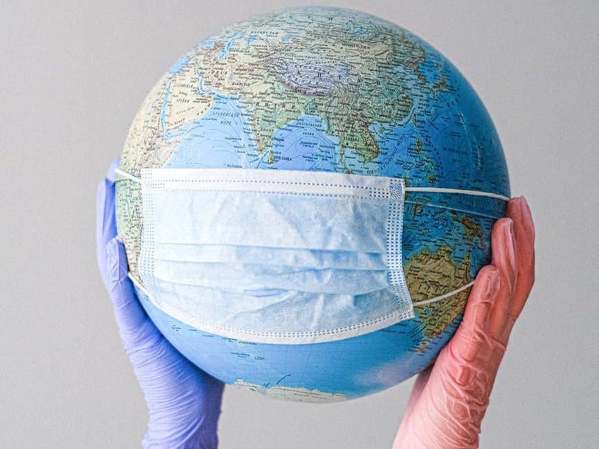 hands with latex gloves holding a globe with a face mask