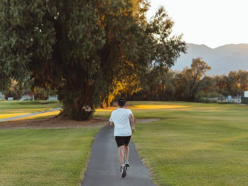 unrecognizable woman jogging along footpath in park