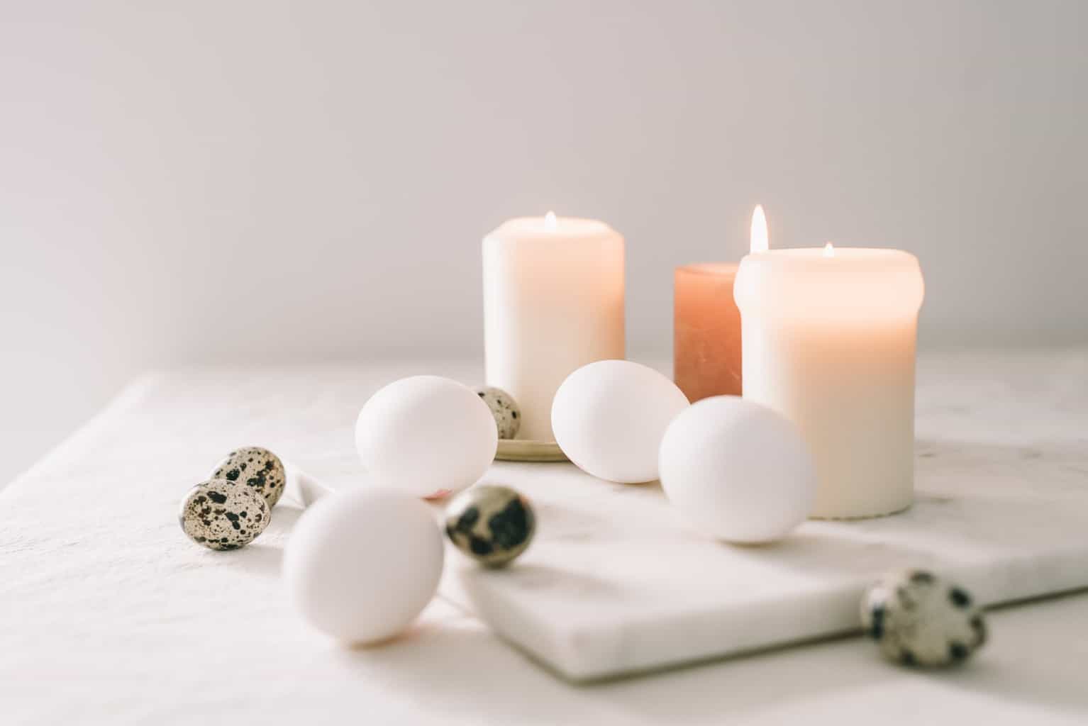 white eggs and quail eggs beside lighted candles