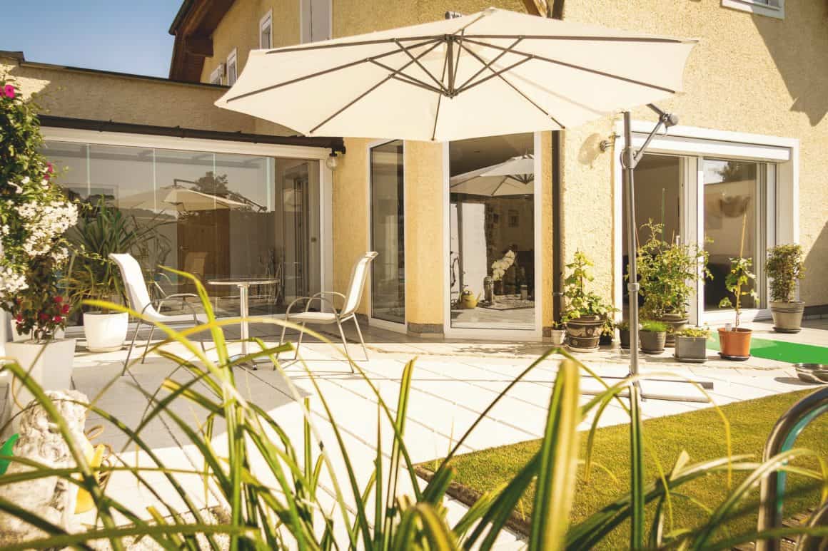 a patio with a white umbrella and chairs