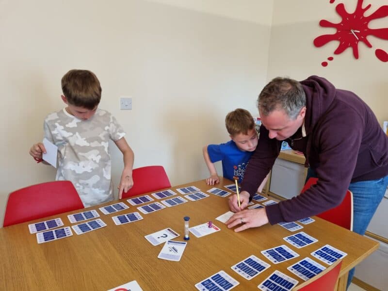 a man writing on a piece of paper on a table with other people