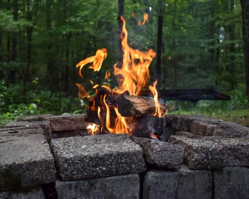 a fire pit with a fire in the middle of the forest