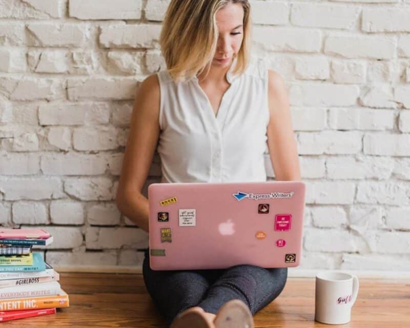 a woman sitting on the floor with a laptop