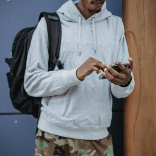 a man wearing a backpack and holding a phone