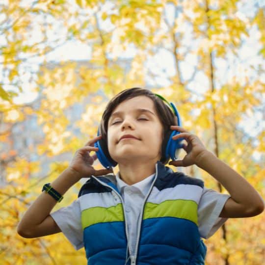 a boy wearing headphones and standing outside