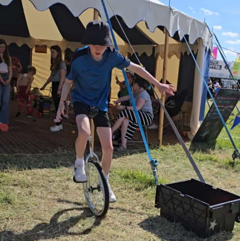 a boy on a unicycle in front of a tent