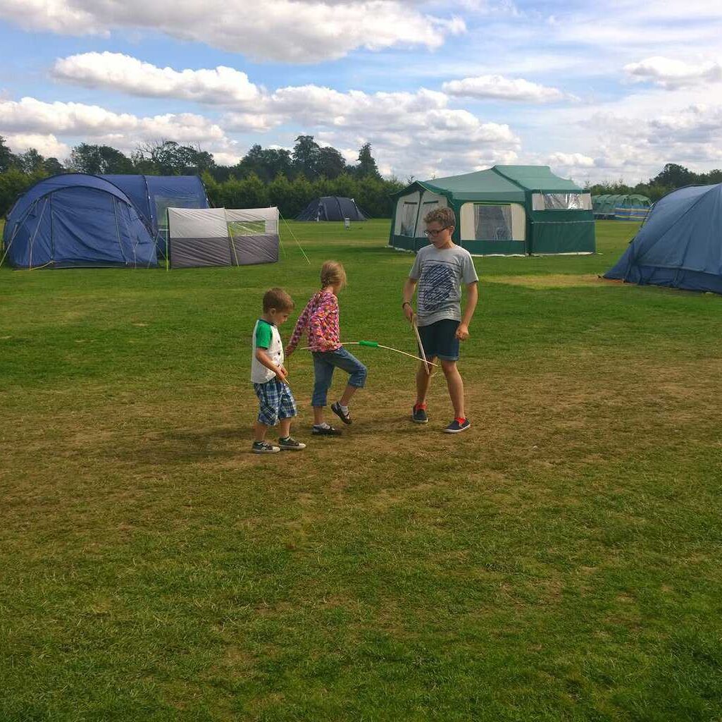 a group of kids playing in a field with tents